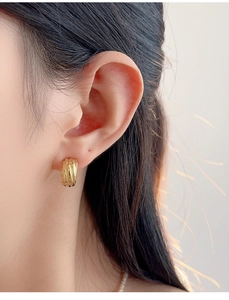 Close-up of gold S925 sterling silver layered spiral earring worn on earlobe