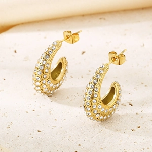 Gros plan sur des boucles d'oreilles ovales en C dorées avec pavé de cristaux brillants
