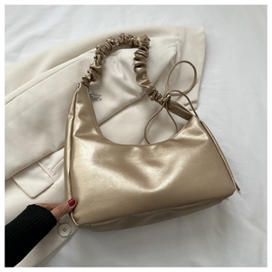 Detail view of champagne gold crescent shoulder bag with unique pleated ruched strap texture