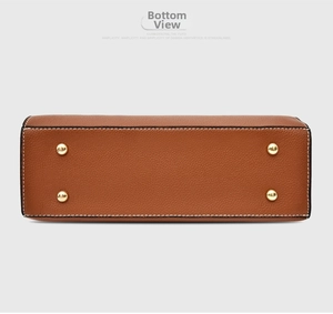 Detail of brown litchi leather bag base with four gold metal protective studs