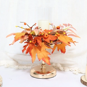 Detail of autumn candle ring with maple leaves, red berries, and glass holder