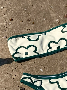 Close-up of strapless floral bikini set on sand showing green flower print detail