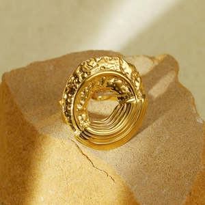 Golden hammer textured hollow round ring in stainless steel displayed on a natural rock