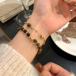 Macro shot of 18K gold plated tiger eye beaded bracelets styled with a gold charm