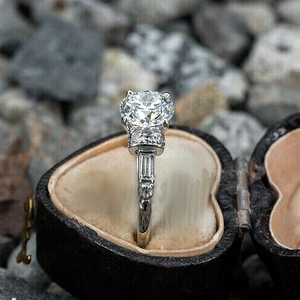 Elegante diamanten verlovingsring met vier klauwen gepresenteerd in een vintage hartendoos