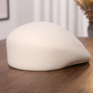 Detailed texture of off-white wool felt flat cap on a rustic wooden surface
