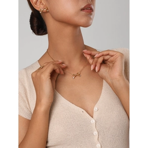 Close-up of elegant gold bow jewelry set with zircon necklace, earrings, and open ring