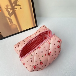 Detail of pink quilted floral makeup bag showing the soft fabric texture and red flower pattern