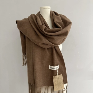 Detail of dark caramel scarf featuring fine cashmere texture and elegant fringe tassels