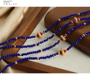 Macro view of blue faceted beads and gold rhinestone pendant on silk and wood tray