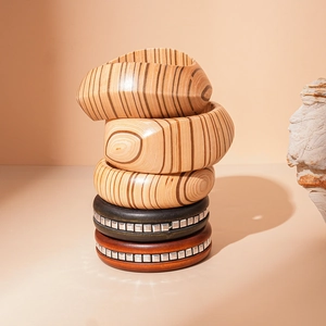 Close-up of stacked wooden bangles with geometric textures and metal rivet accents
