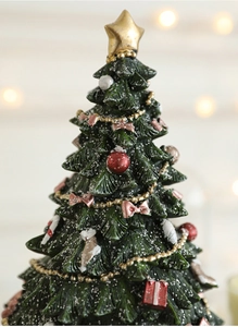 Macro detail of miniature resin Christmas tree with faux snow, golden star and tiny ornaments