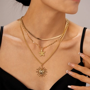Close-up of layered gold necklace set with starfish and sun face pendants on model
