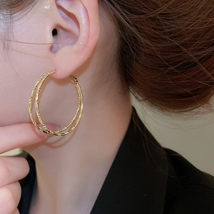 Close-up of elegant gold double-layered bamboo hoop earrings worn by a model