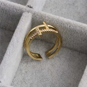 Golden double cross open ring with cubic zirconia inlay on grey velvet display case