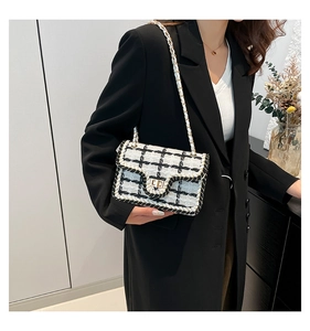 Dettaglio della borsa a tracolla in tweed bianco e nero con chiusura quadrata dorata