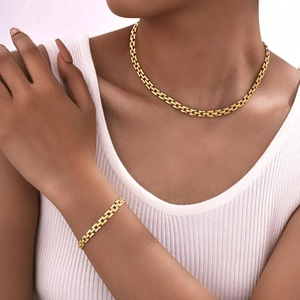 Detail view of gold watchband style necklace and bracelet set on model neckline