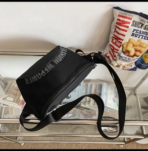Détail d'un sac bandoulière en nylon noir avec sangle réglable et logo imprimé