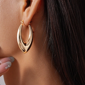 Close-up of minimalist gold teardrop hoop earring worn by a model in a luxury style