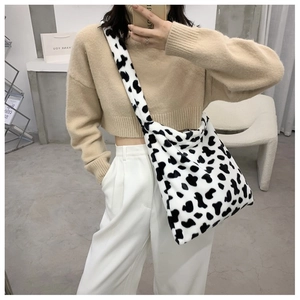 Close-up of cow print plush tote bag showing soft faux fur texture and wide strap