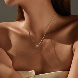 Elegant gold necklace with a round yellow gemstone pendant worn by a model