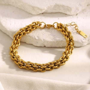 Macro detail of 18K gold plated lantern link chain bracelet on a white textured stone base
