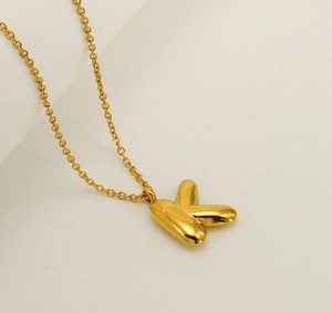 Close-up of polished golden balloon letter K pendant necklace with delicate O-chain