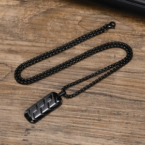 Detail of black stainless steel rectangle pendant with industrial geometric arrow texture