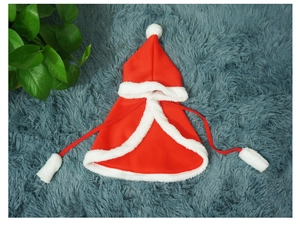 Detail of red plush pet Christmas cape with white faux fur trim and pom-pom ties