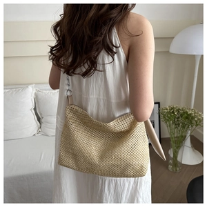 Detail of woven straw tote bag with silver chain strap on white dress for summer