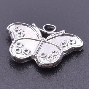 Macro shot of polished silver stainless steel butterfly pendant with embossed details