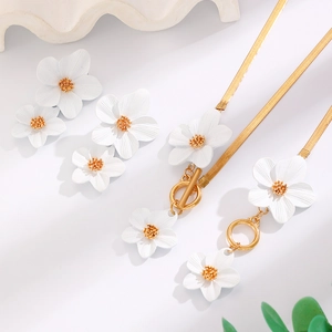 Detailed view of white floral necklace and earring set with golden snake chain elements