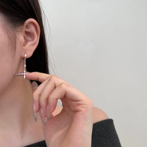 Close-up of S925 sterling silver cross earrings with sparkling central zircon on a model