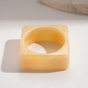 Macro side view of a minimalist cream square resin bangle with cloud-like textures