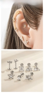 Detailed close-up of F136 titanium ear studs with butterfly and dolphin zircon shapes