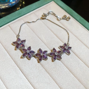 Detailed view of five purple zircon flowers on a silver adjustable bracelet in a gift box
