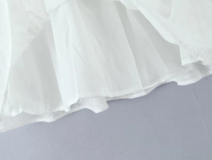 Detailed close-up of white dress hem featuring delicate floral embroidery and soft lining