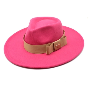 Detail of peach pink wool fedora hat with satin ribbon and gold bee accessory