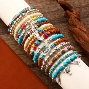 Detail of stacked bohemian beaded bracelets with turquoise, wood beads and metal charms