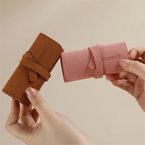 Compact microfiber jewelry roll organizers in brown and pink held by hand