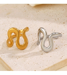 Detailed view of wave shaped gold and silver adjustable rings on a stone tile