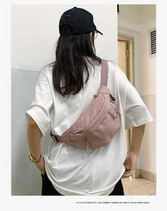 Close-up of a pink nylon crossbody bag worn on the back with an adjustable wide strap