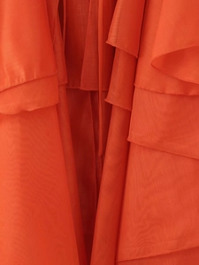 Vue détaillée du tissu en mousseline orange superposé et des finitions de couture de qualité