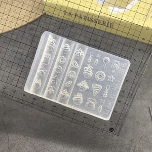 Macro detail of transparent silicone nail art mold with miniature dessert and cutlery shapes