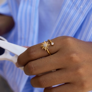Close-up of a gold sunflower open ring with white zircon on a model's hand