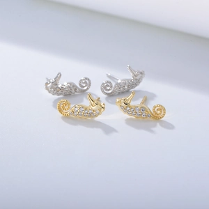 Detail view of gold and silver seahorse earrings with shimmering white cubic zirconia