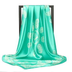 Detailed texture of green paisley square scarf with silk finish on black frame