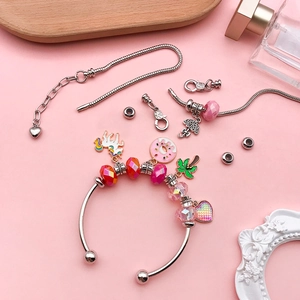 DIY charm bracelet set with silver bangles and colorful unicorn pendants on pink background