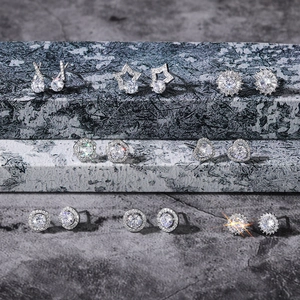 Macro view of assorted silver zircon stud earrings with flower and star shapes on marble