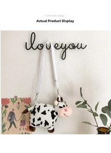 Detail of cute cow plush crossbody bag with adjustable white strap on a wall hook